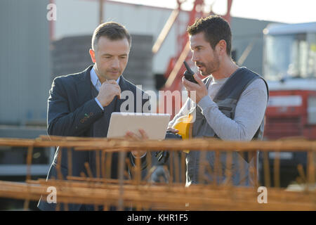 middle-aged male worker using walkie-talkie with colleague Stock Photo