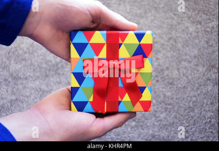 A man holding a small, colorful gift card box out. Stock Photo