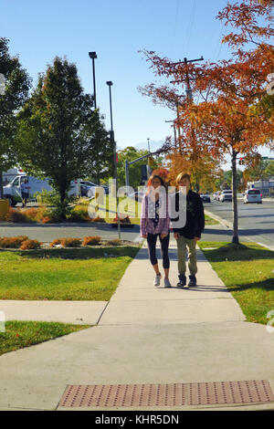 A boy and girl walking home from school on a fall day. Stock Photo