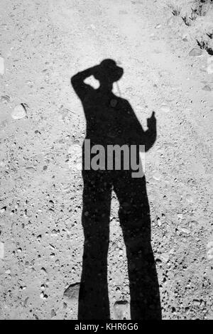 A silhouette of a cowboy tipping his hat and holding a six shooter in black and white. Stock Photo