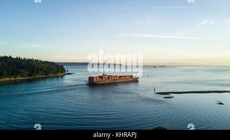 Big Cargo Ship fully loaded is leaving port and passing by Stanley Park, Vancouver, British Columbia, Canada. Stock Photo