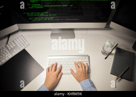 High angle view of unrecognizable programmer using modern computer in order to write code while sitting at office desk Stock Photo