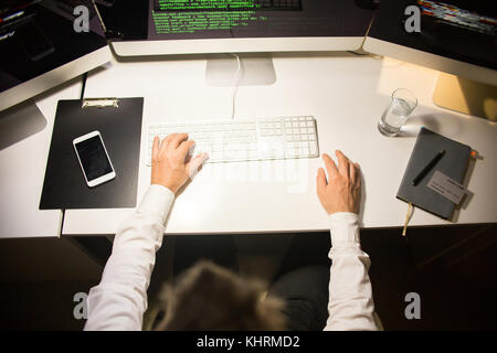 High angle view of male programmer wearing white shirt putting finishing touches in brand new computer app while sitting at desk in modern office Stock Photo