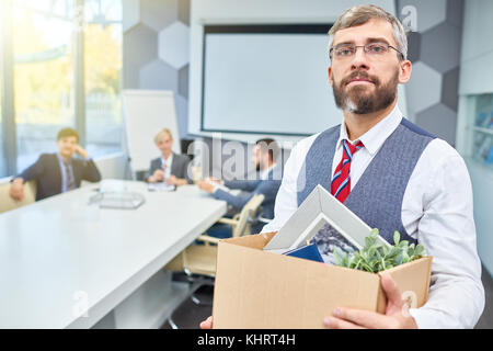 Portrait of mature bearded businessman holding box of personal belongings being fired from work in company, copy space Stock Photo