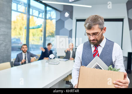 Portrait of depressed mature businessman holding box of personal belongings being fired from work in company, copy space Stock Photo