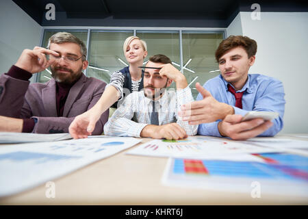 Portrait of three business people sitting at meeting table discussing financial problems analyzing financial and marketing statistics for annual repor Stock Photo