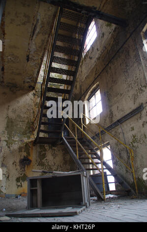 Stairs with yellow railing in a ruined industrial interior. Abandoned old factory. Stock Photo