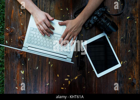 Laptop, camera on wooden background. Flat lay of working place of freelancer or individual entrepreneur outside Stock Photo