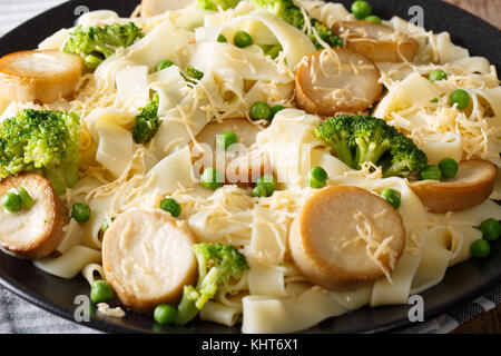 Fettuccine pasta with mushrooms king oyster, broccoli and peas close-up on a plate. horizontal Stock Photo