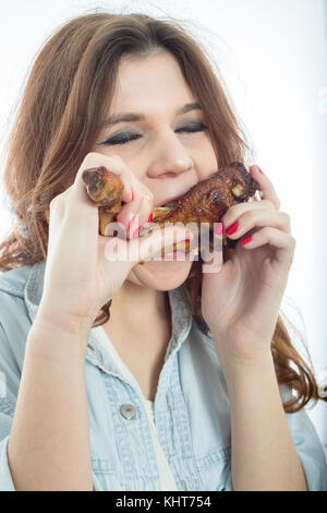 fun young woman eats fried chicken thigh on white background isolated Stock Photo