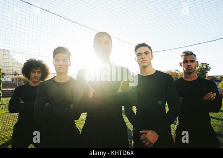 Young football team standing together in a line on soccer field. football players during practice. Stock Photo