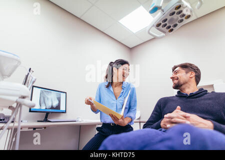 Happy dentist and patient at dental clinic. Smiling doctor and patient discussing report at dental clinic. Stock Photo