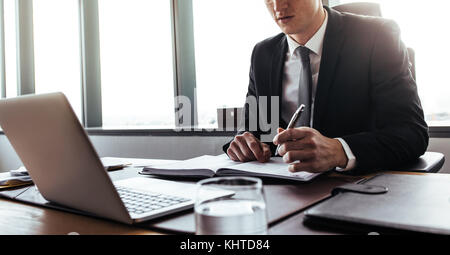 Close up of businessman hands writing notes while working on laptop. Corporate professional making notes in office. Stock Photo
