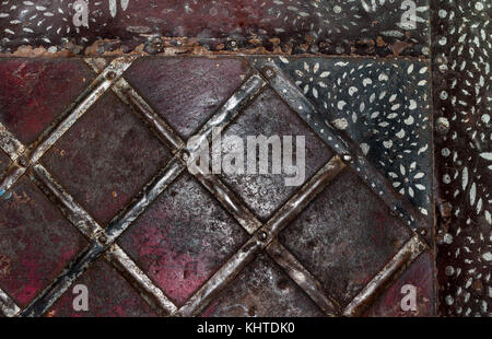 Close-up squares on old rusty metal surface and black painted stripes in top right corner. Stock Photo