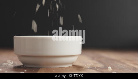 closeup of grating aged parmesan in white bowl on wood table Stock Photo