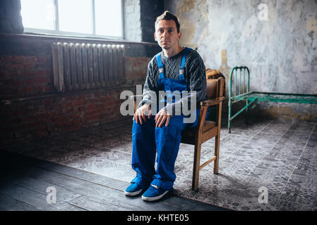 Crasy man in uniform sitting in the chair, psycho patient. Mentally ill people concept, stressed human Stock Photo