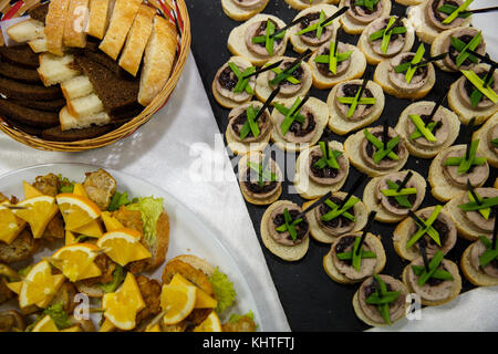 Two plates with snacks and bread on a buffet table. Selection of tasty bruschetta or canapes on toasted baguette and quark cheese topped with fried me Stock Photo