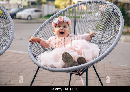 Little girl sits on a armchair outdoor. Stock Photo