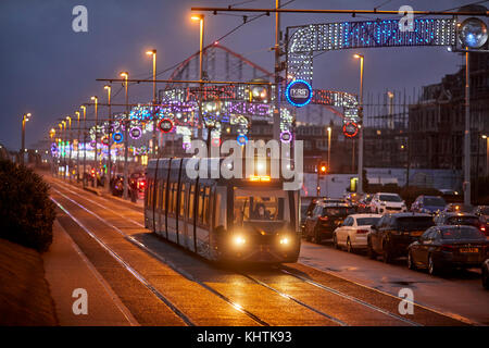 Blackpool tram running along the promenade at night with the Pleasure beach behind, in Lancashire Stock Photo