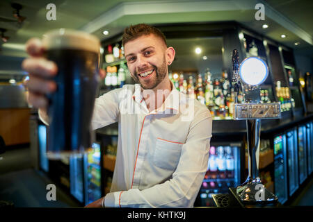 A barman holing a pint at Marston's The Old Duke pub in Southport in Merseyside Stock Photo