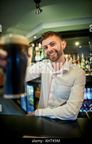 A barman holing a pint at Marston's The Old Duke pub in Southport in Merseyside Stock Photo