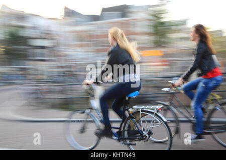 Girls cycling along the Prinsengracht canal, in Amsterdam, the Netherlands Stock Photo