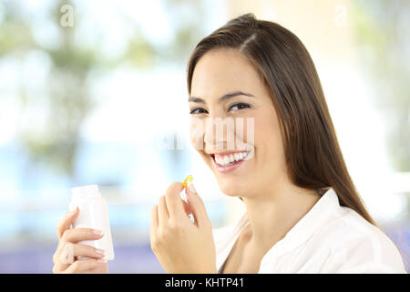 Portrait of a happy woman holding a vitamins pill and bottle Stock Photo