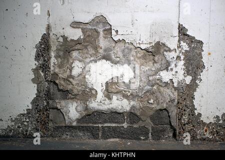 Crumbling plaster and exposed brickwork on a wall in my building's underground parking garage. Stock Photo