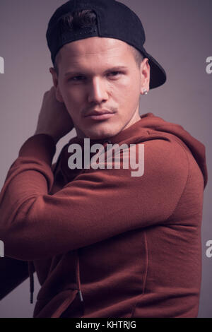 one young man, early 20s,  boyish looks, posing in studio, casual clothes, sweatshirt cap, upper body shot portrait Stock Photo