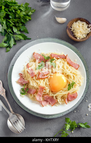 Spaghetti carbonara pasta with egg sauce, bacon and grated parmesan cheese  - homemade healthy italian pasta on grey concrete background