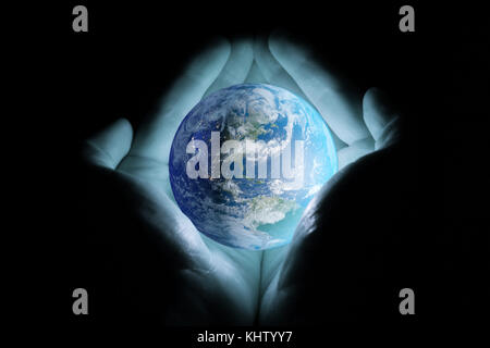 Men's hands holding the planet earth rotated the continents of North and South America with a blue glow on a black background. Stock Photo