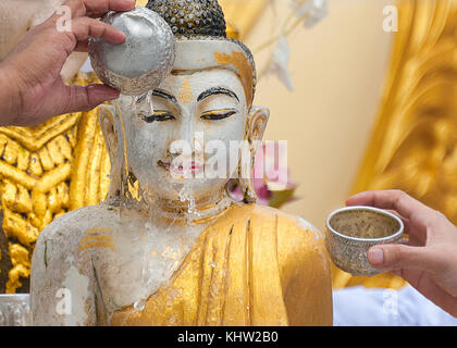 BATHING BUDDHA STATUE FOR BLESSING – A RELIGIOUS RITUAL. Pouring water onto Buddha statue is a gesture of worship to the lord Buddha. Stock Photo