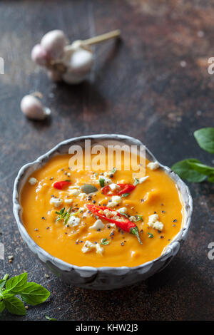 Pumpkin spicy cream soup with cheese and seeds on a wooden table on a ...