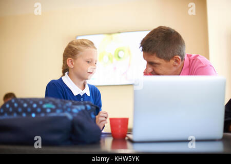 Father helping daughter with homework at kitchen counter Stock Photo