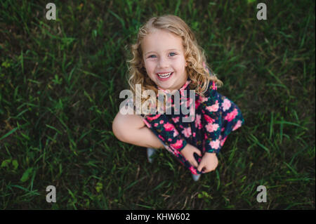 Overhead portrait of blond haired girl sitting on grass Stock Photo