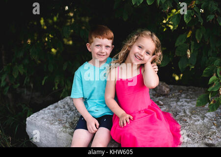 Portrait of boy and sister sitting on rock Stock Photo