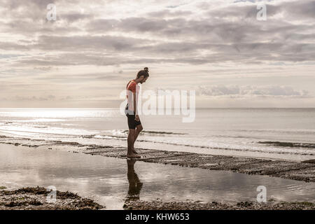 Man on shoreline looking away at view of sea Stock Photo