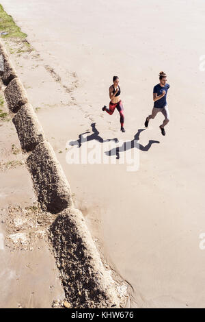Young man and woman running along beach, elevated view