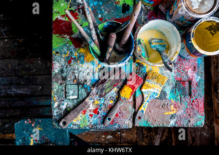 Paint brushes and pots of paints on workshop table Stock Photo