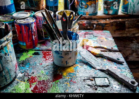 Paint brushes and pots of paints on workshop table Stock Photo