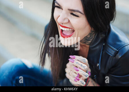 Portrait of young woman laughing, tattoos on neck and hand Stock Photo
