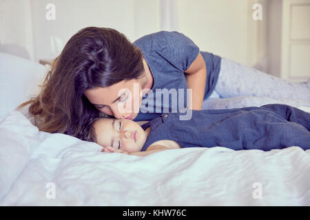 Mother kidding sleeping toddler on cheek Stock Photo