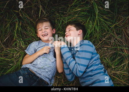 Brothers lying on grass together Stock Photo