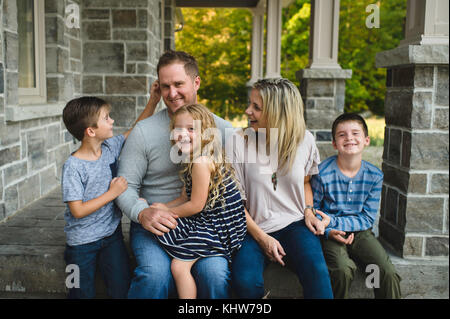 Family of five sitting on front porch Stock Photo