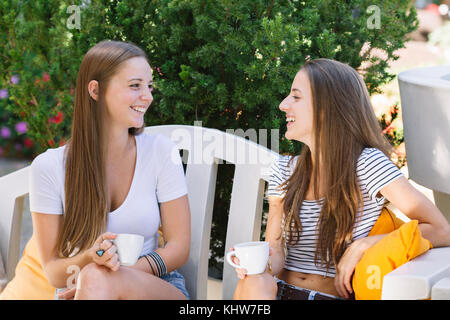Two young female friends chatting over coffee at sidewalk cafe Stock Photo