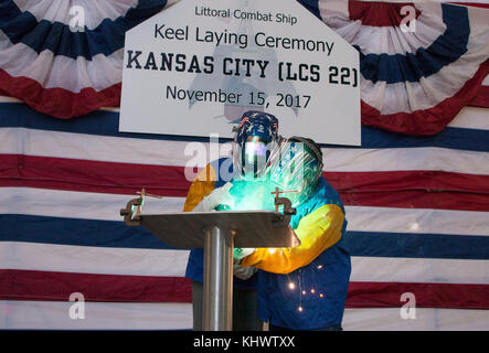 171115-N-N0701-002  MOBILE, Ala. (Nov. 15, 2017) Missouri native Tracy Davidson, spouse of Adm. Phil Davidson, commander of  U.S. Fleet Forces Command, and ship's sponsor of the future Independence-class littoral combat ship USS Kansas City (LCS 22), and Austal USA A-class welder Adan Silva-Garibay etches her initials into the ship's keel plate during a keel laying ceremony at the Austal USA shipyard. The keel laying ceremony symbolically recognizes the joining of modular components and the ceremonial beginning of the ship. USS Kansas City is the second ship to be named for Kansas City, Mo., t Stock Photo