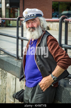 Old man with a thick beard and a captain's cap observing ships on the ...