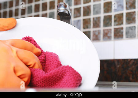 Close-up view of hands in rubber gloves washing dishes with sponge. Housework concept Stock Photo