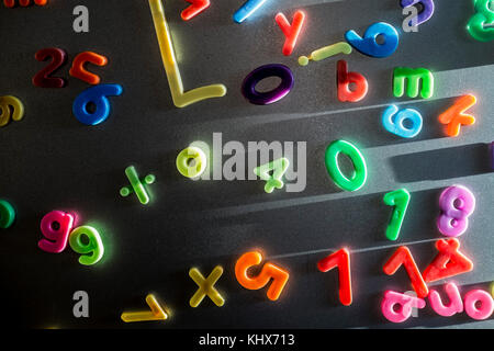 Colourful plastic magnetic letters and numbers stuck on a refrigerator door. Stock Photo