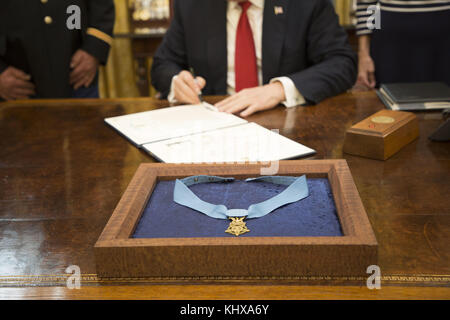 President Donald J. Trump signs the Medal of Honor citation for Retired Army Capt. Gary M. Rose, in the Oval Office at the White House, Monday, October 23, 2017, in Washington, D.C., prior to the presentation of the Medal of Honor to Rose  People:  President Donald J. Trump